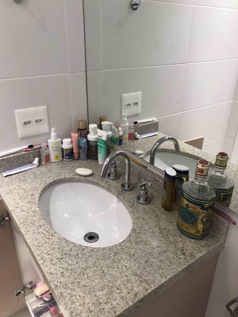 Banheiro da suíte feminina antes do home staging com excesso de itens e pouca padronização estética